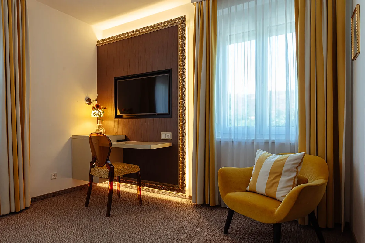 Pokoj v hotelu Goritschniggs Hotel se žlutým křeslem