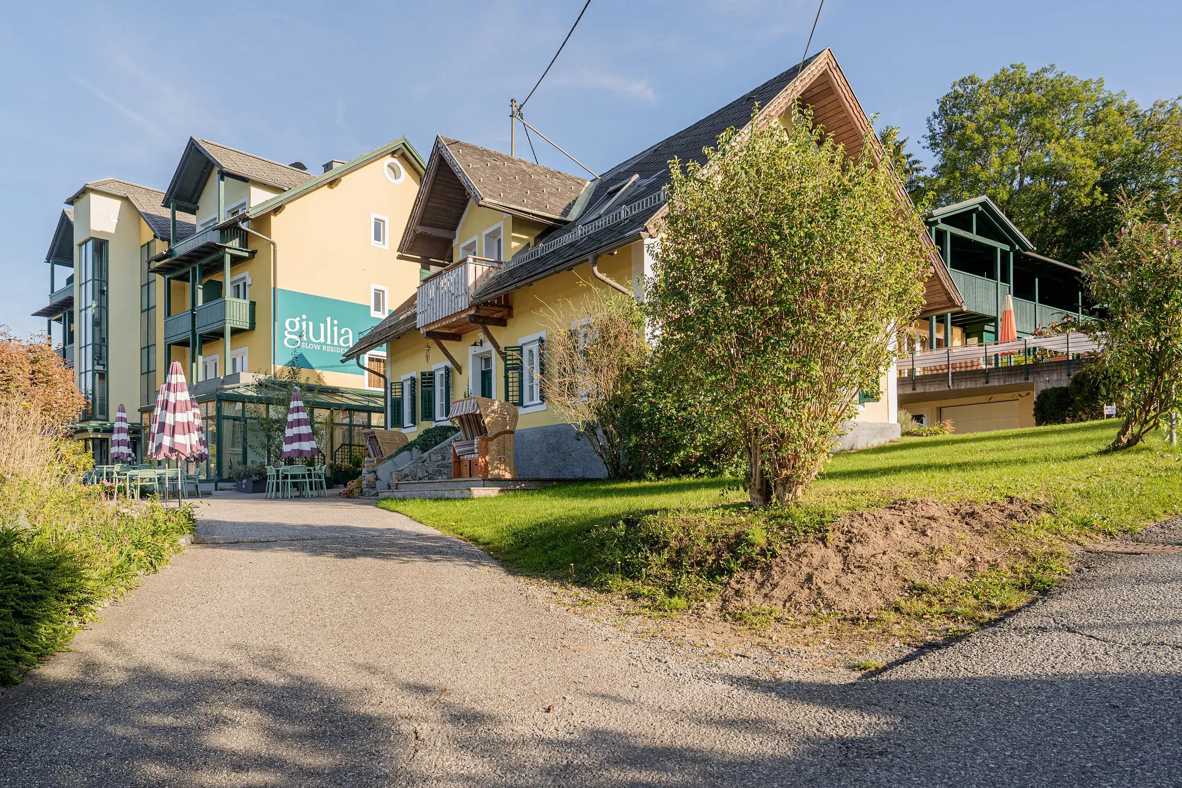 Giulia Slow Residence s nápisem na fasádě a slunečníky v zahradě