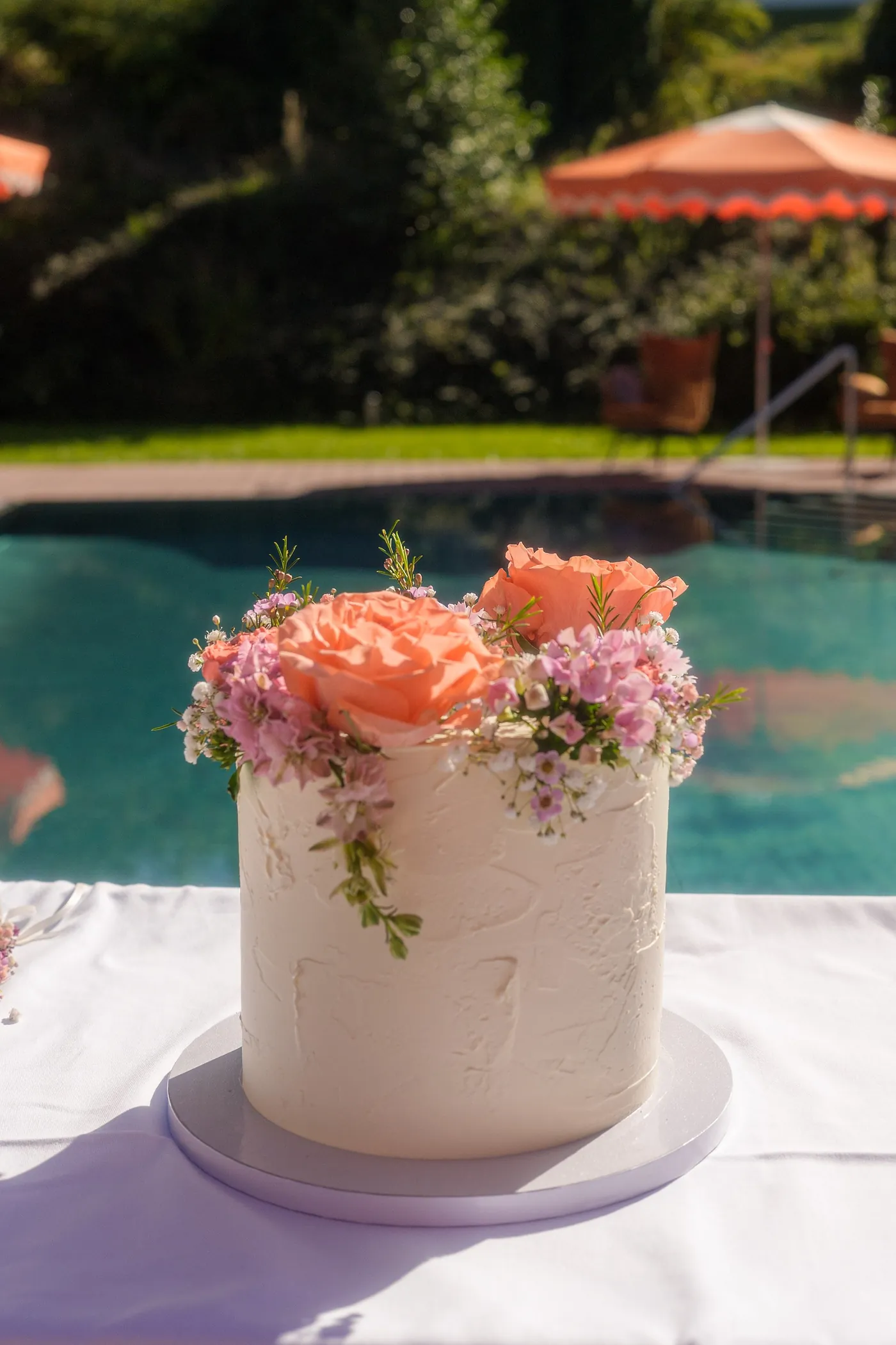 Hochzeitstorte mit Blumen am Pool